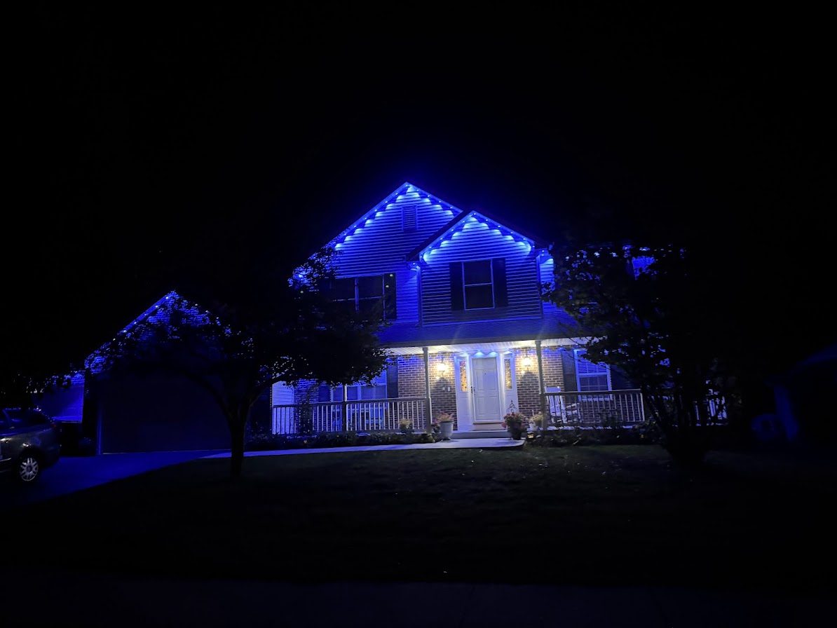 House at night with blue permanent roofline lighting