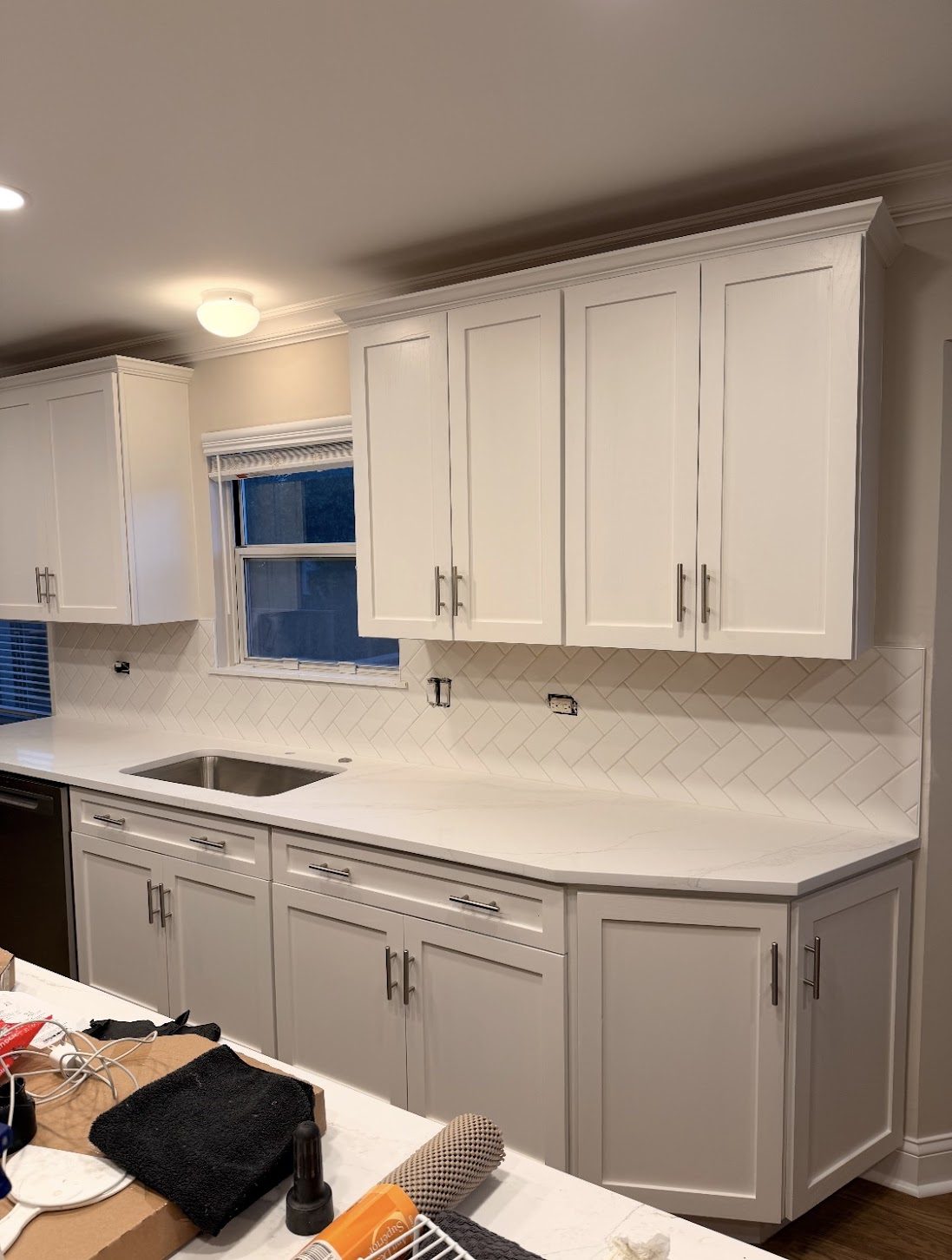 White kitchen backsplash laid in a herringbone pattern