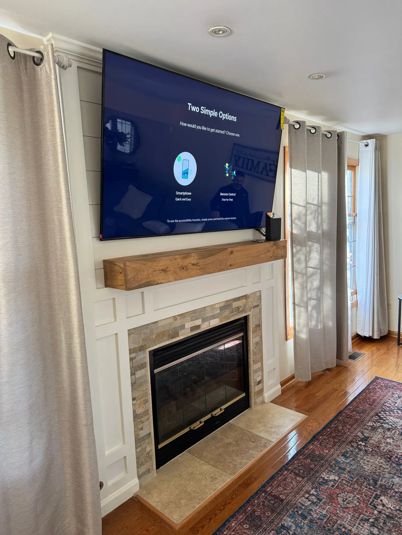 Finished fireplace update with wooden mantel, white trim panels, and wall-mounted TV