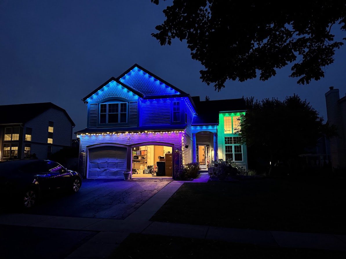 Two-story house at night with blue and purple permanent roofline lighting